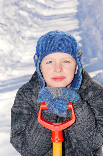 Jongen met een schop na een daling van de sneeuw. — Stockfoto