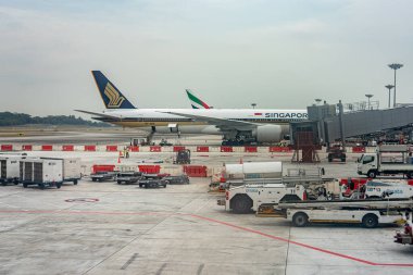 Changi, Singapore - 28 Aug, 2019: Airliner at the gate being prepared for takeoff with many utility vehicles parked and loading.