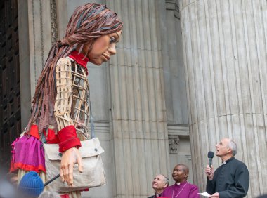 Londra, İngiltere. 23 Ekim 2021. Amal, dev mülteci kuklayı Londra 'daki St. Paul Katedrali' nde Dean, Dr. David Ison karşılıyor. Yürüyüş, yerlerinden edilen çocukları temsil eden sanatsal bir tepkidir..