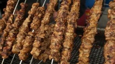 Kebap yapmak için şişlenmiş etin açılı yan görüntüsü, portatif bir ızgaranın üzerinde kızartılıyor..