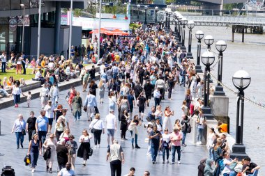 Londra, İngiltere. 11 Haziran 2022. Londra 'daki Tower Bridge yakınlarındaki Thames Nehri' nin güney kıyısındaki Queen 's Walk' ta yabancı turistler ve gezginlerle dolu gezinti güvertesi boyunca yürüyüş yapıyorlar.. 