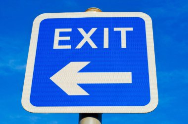 Açık mavi gökyüzüne karşı sol tarafı gösteren ok sembollü EXIT yol tabelası.