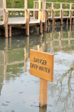 Wooden DANGER DEEP WATER sign in middle of lake.