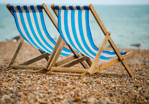 Two deck chairs on the pebble beach at Brighton, UK.