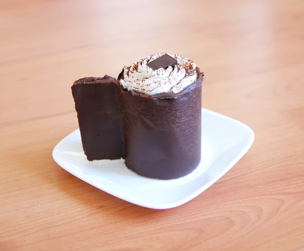 Copa de pastel de chocolate en un plato blanco en la mesa de madera — Foto de Stock