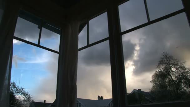 Zonsondergangen door oude windows in huis. regenwolken ontwikkelen zoals storm rollen. — Stockvideo