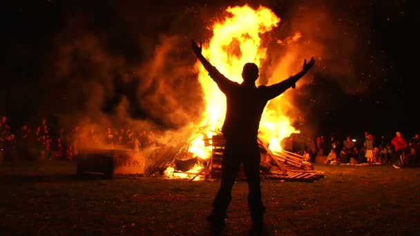 Homem caminha até o fogo grande e coloca ambos os braços para cima . — Vídeo de Stock
