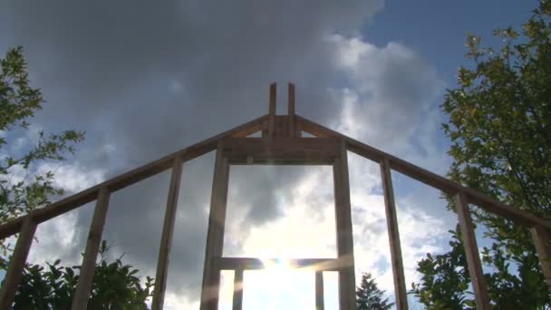 Time Lapse of clouds and sun shining through window on framework of new construction. — Stock Video