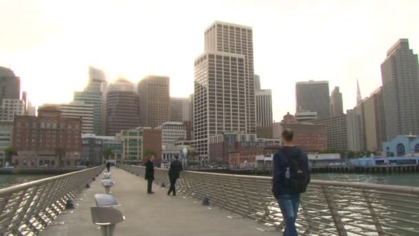 San francisco - circa november 2011: centrum van fisherman's wharf met man en vrouw paar wandelen down pier 14 in san francisco, Californië op heldere, zonnige dag als de zon ondergaat achter hoge ingebouwde — Stockvideo