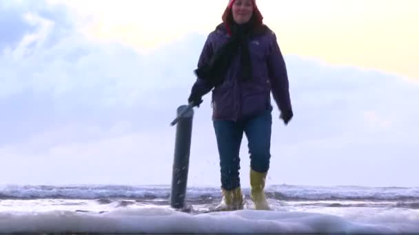 Femme avec pistolet clamming marche océan Pacifique à la recherche de palourdes rasoir au coucher du soleil, zoom arrière et incliner vers le ciel .