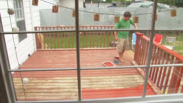 Man paints back deck vibrant red in time lapse. — Stock Video