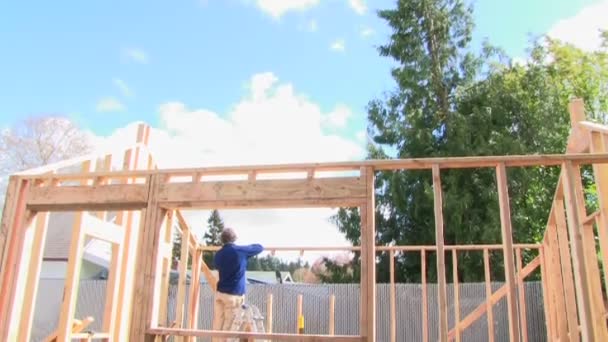 Мужчина строит деревянный дом — стоковое видео