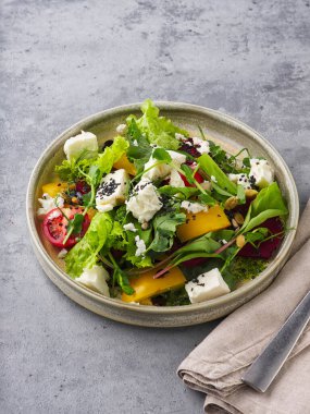 Fresh vegetable salad with feta cheese and on a stone background
