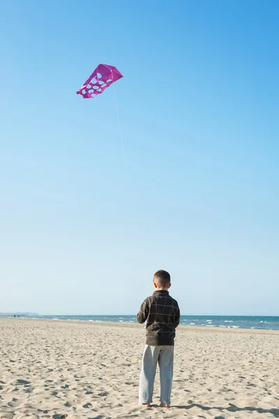 Junge spielt mit Drachen am Strand. — Stockfoto