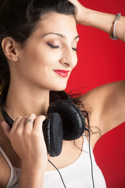 Mooi meisje luisteren naar muziek tegen rode achtergrond. — Stockfoto