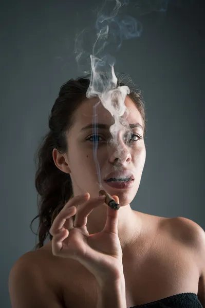 Kvinna röka cigarr mot mörk bakgrund. Studio mode phot — Stockfoto