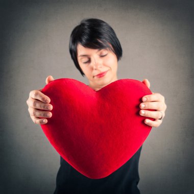 karşı kırmızı kalp tutan çekici esmer kadın portresi