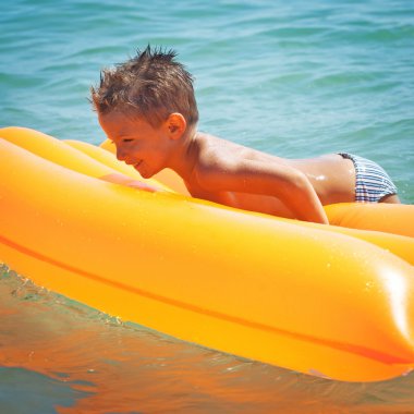 havalı yatak ile plajda oynayan çocuk.