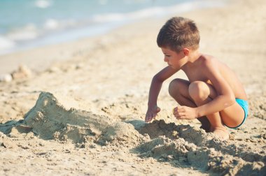 güneşli bir günde plajda oynayan çocuk.