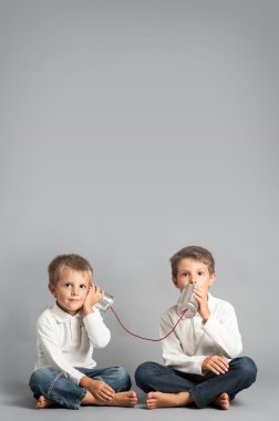 jonge broers praten met blikje telefoon.
