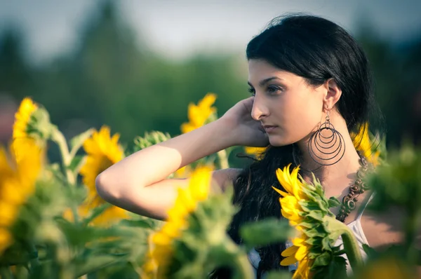 Jonge mooie vrouw in een zonnebloem veld met witte jurk. — Stockfoto