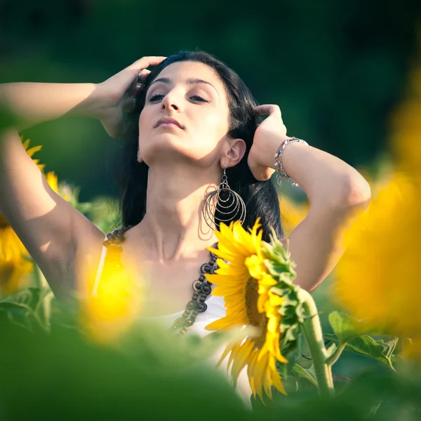 Junge schöne Frau in einem Sonnenblumenfeld mit weißem Kleid. — Stockfoto