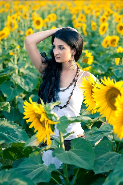 Jonge mooie vrouw in een zonnebloem veld met witte jurk. — Stockfoto