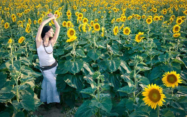 Молода красива жінка на соняшниковому полі з білою сукнею . — стокове фото