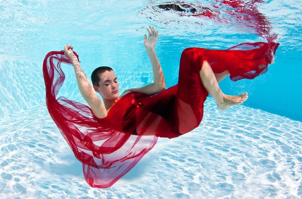 在游泳池中的红色面纱的水下女人时尚人像 — 图库照片