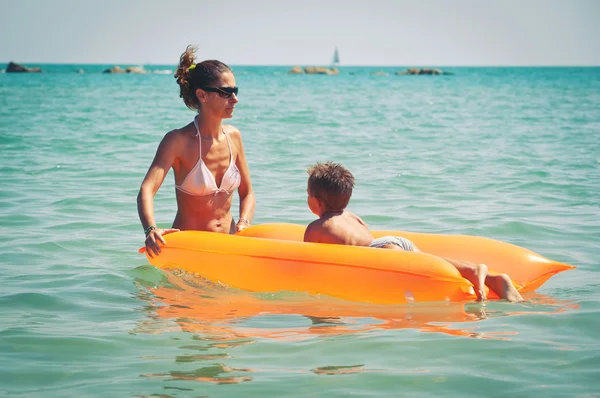 Mutter und Sohn spielen am Strand mit Luftmatratze. — Stockfoto