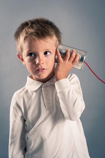 Young boy listen to tin can telephone.