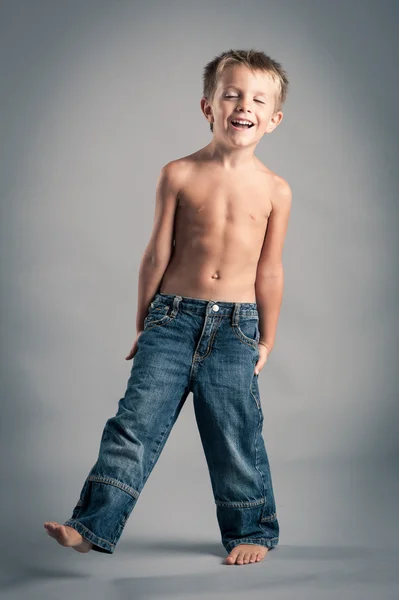 若い男の子は笑っています。灰色の背景とのスタジオ ポートレート. — ストック写真