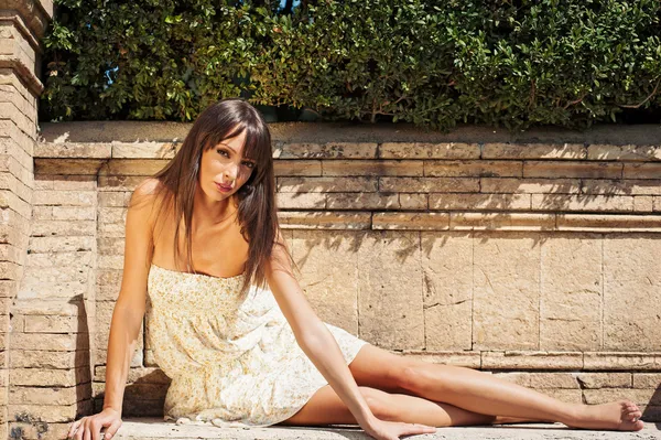 Vacker flicka poserar om på en tegelvägg. — Stockfoto