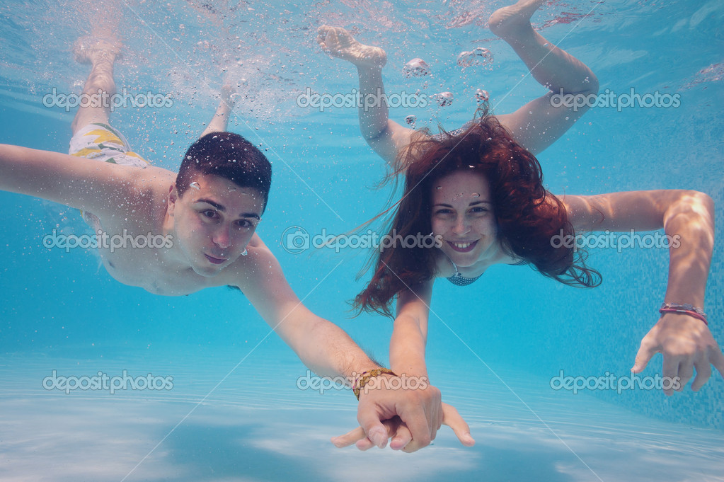 Underwater couple holding hands in swimming pool. — Stock Photo © pio3