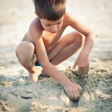 güneşli bir günde plajda oynayan çocuk.