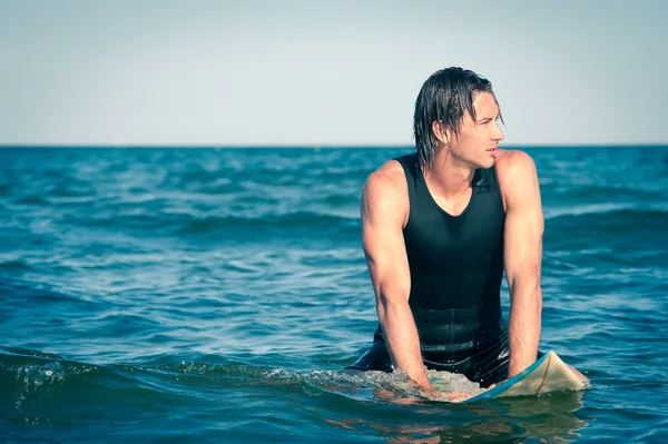 Jovem surfista relaxante na água com uma prancha de surf . — Fotografia de Stock