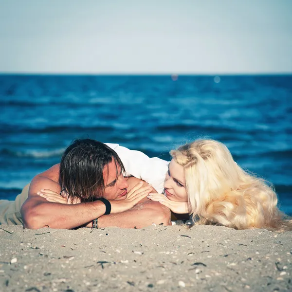 Молода пара в любові розслабляється на пляжі . — стокове фото