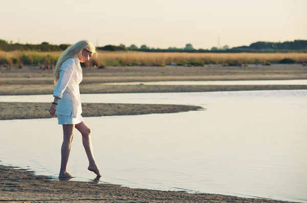 Schöne junge Frau am Strand bei Sonnenuntergang. — Stockfoto