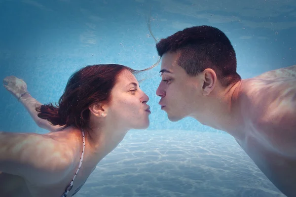 Casal subaquático beijando na piscina . — Fotografia de Stock
