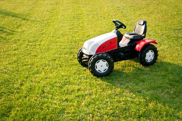 Traktor zabawka na białym tle nad trawa. — Zdjęcie stockowe