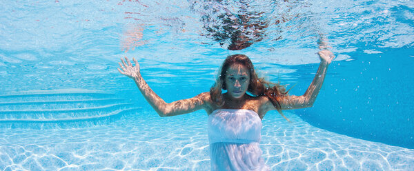 Портрет подводной женщины с белым платьем в бассейне
