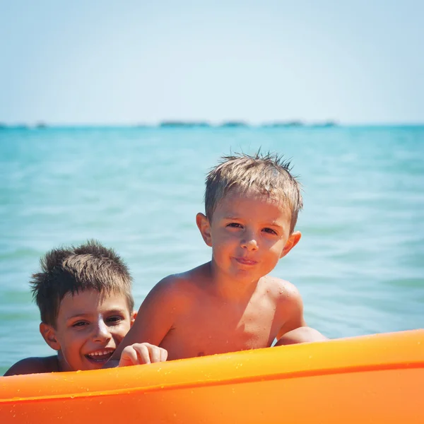 Dois irmãos brincando na praia com colchão de ar . — Fotografia de Stock