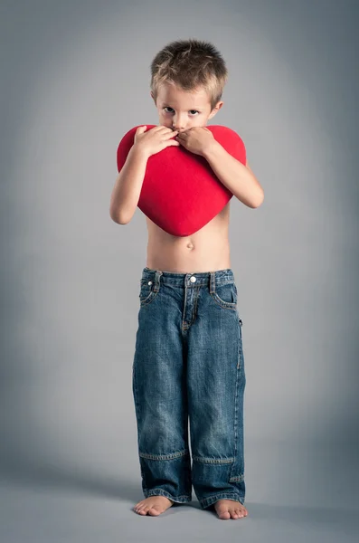 Kleiner Junge, der mit rotem Herzen spielt. Valentinstag-Konzept. — Stockfoto