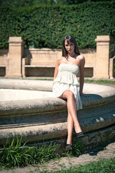 Intens mooi meisje portret buiten zitten op een fontein — Stockfoto