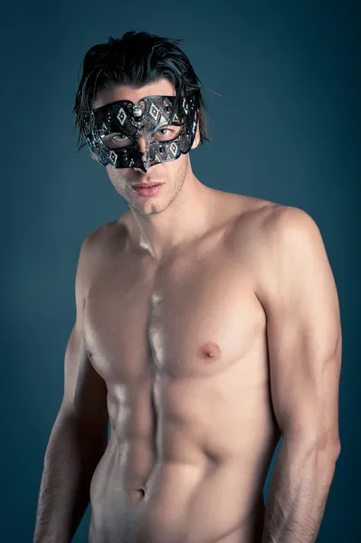 Portrait of young man shirtless with carnival mask against dark background — Stock Photo, Image