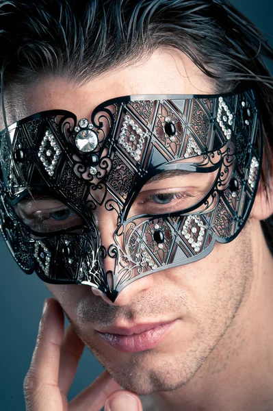 Close up portrait of young man with carnival mask against dark background — Stock Photo, Image