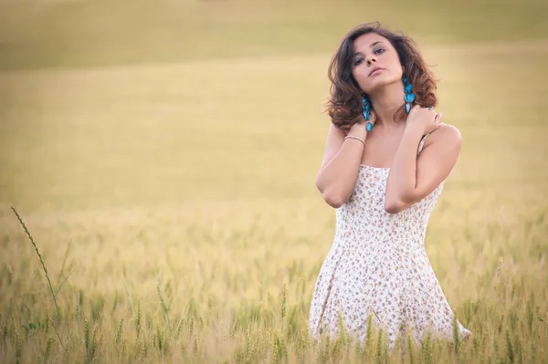 Unga vackra kvinnan i ett vete fält med vit klänning — Stockfoto