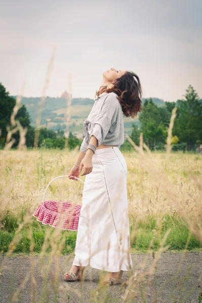 Mulher bonita nova em um campo de trigo com cesta de cerejas — Fotografia de Stock