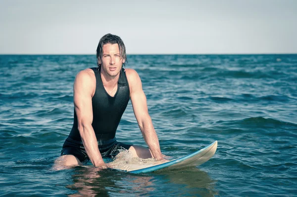Jovem surfista relaxante na água com uma prancha de surf — Fotografia de Stock