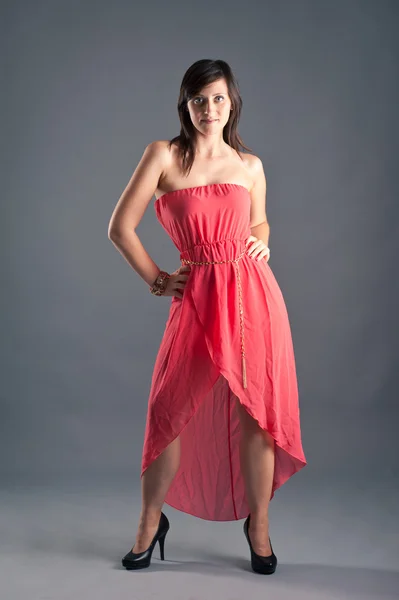 Gri arka planı kırmızı elbise ile güzel bir kadın — Stok fotoğraf